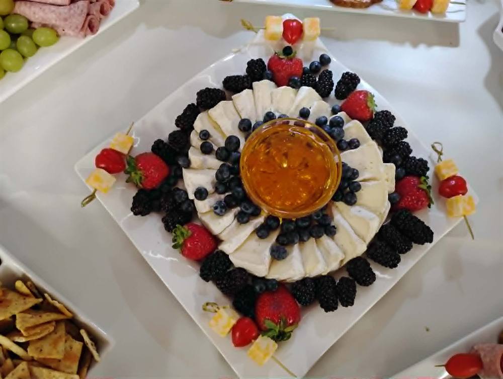 Brie cheese plated with fresh berries and honey drizzle